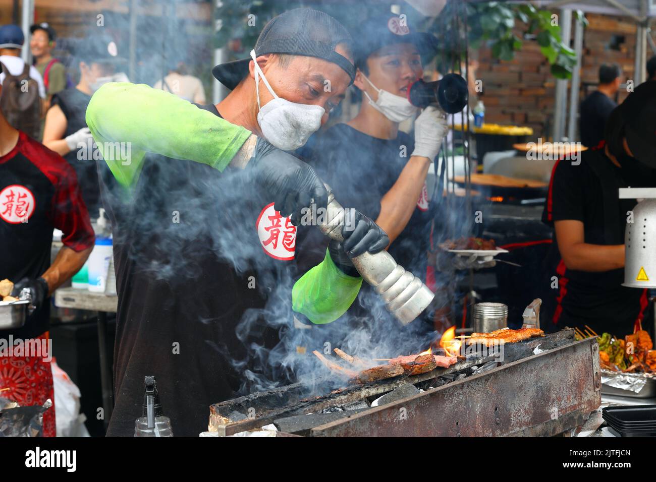 Un chef Yakitori Tatsu prépare kushiyaki et yakitori sur un konro avec du charbon de bois binchotan à une foire de rue, New York. Brochettes sur un grill au charbon de bois. Banque D'Images