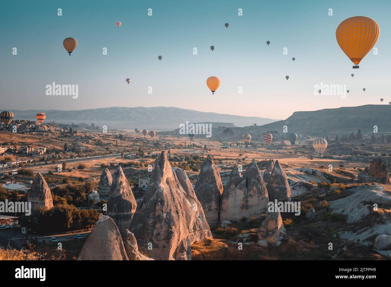 Lever de soleil en Cappadoce - Turquie Voyage arrière-plan. Des ballons d'air chaud lumineux survolent des maisons de grottes et de célèbres champignons de pierre à plusieurs têtes dans le parc national de Göreme. Tourisme, vacances, loisirs, destination Banque D'Images