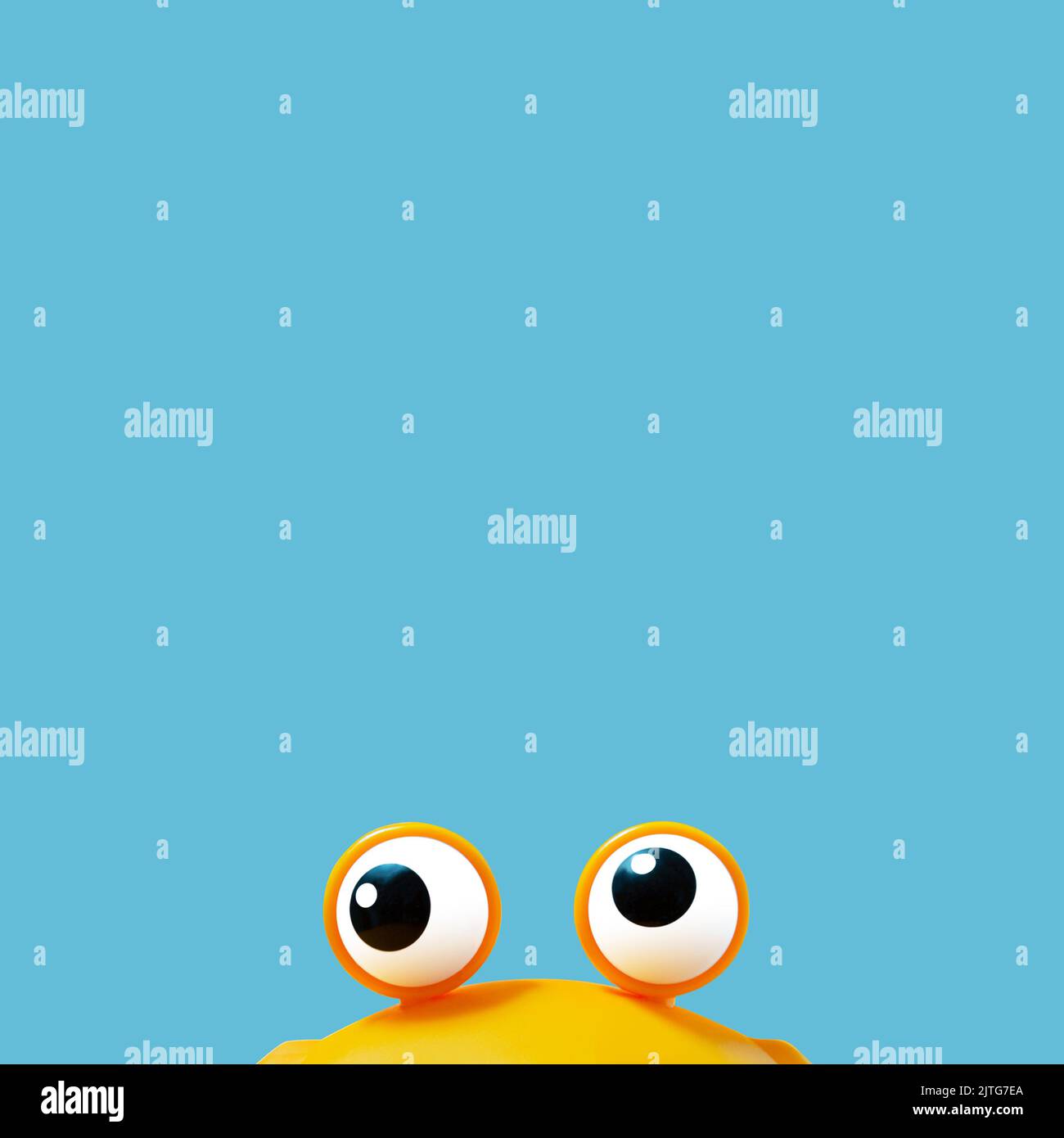 Adorable jouet jaune monstre avec de grands yeux avec un fond bleu pastel derrière. Conception conceptuelle. Banque D'Images
