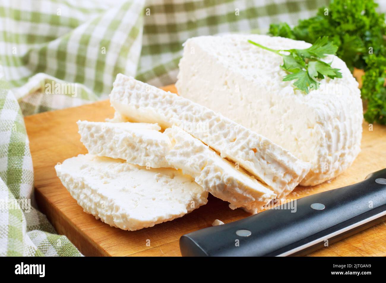 Tranches de fromage cottage frais et persil vert frais sur planche à découper en bois. Produits laitiers, aliments sains. Banque D'Images