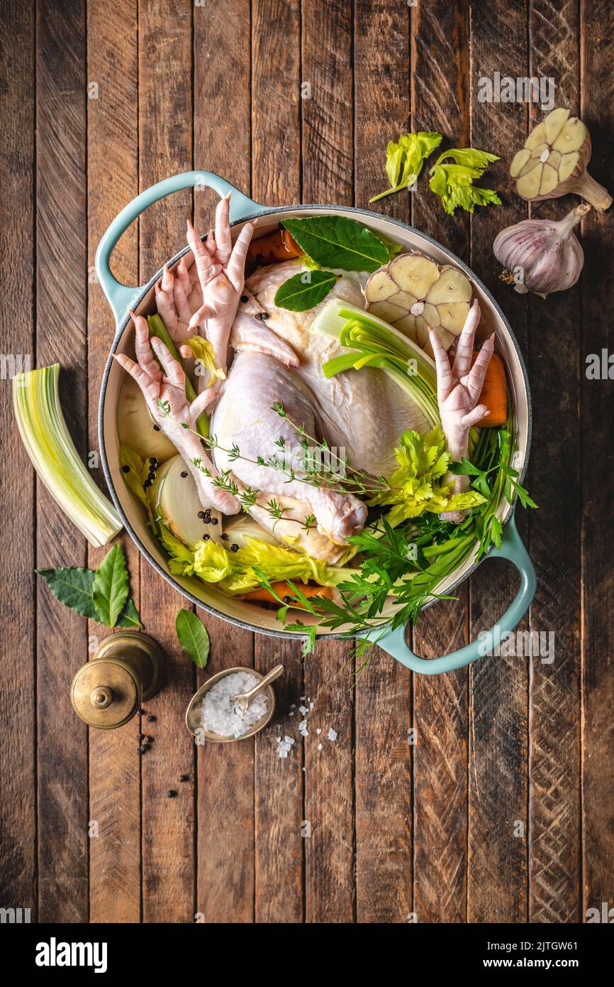 Morceaux de poulet crus, pieds de poulet et légumes au four hollandais pour bouillon de poulet Banque D'Images