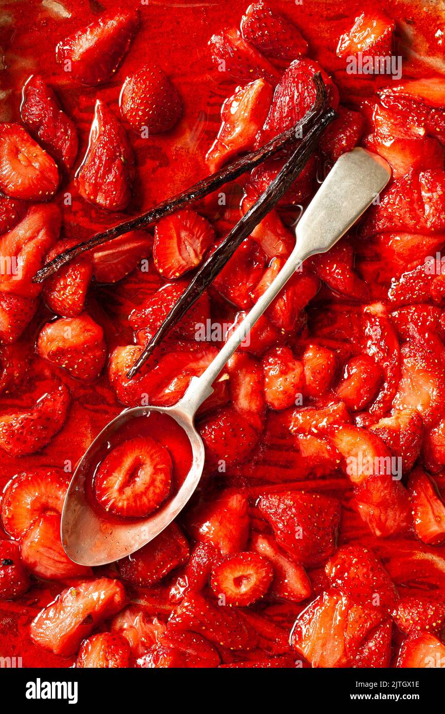 Compote de fraise sur une plaque à pâtisserie avec une gousse de vanille et une cuillère. Banque D'Images