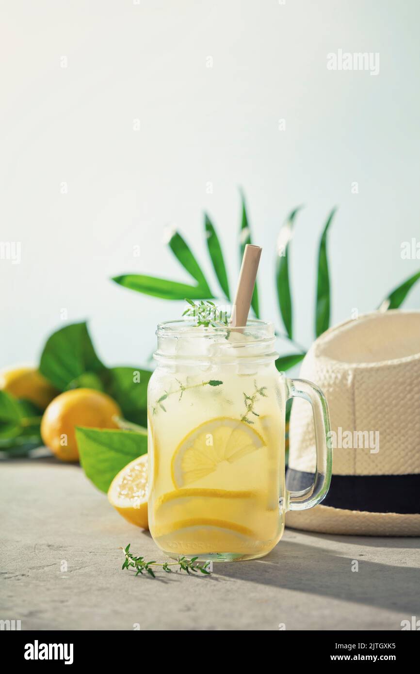 Limonade, chapeau d'été et fruits et feuilles tropicaux de près. Cocktails d'été avec ciel bleu sur fond Banque D'Images