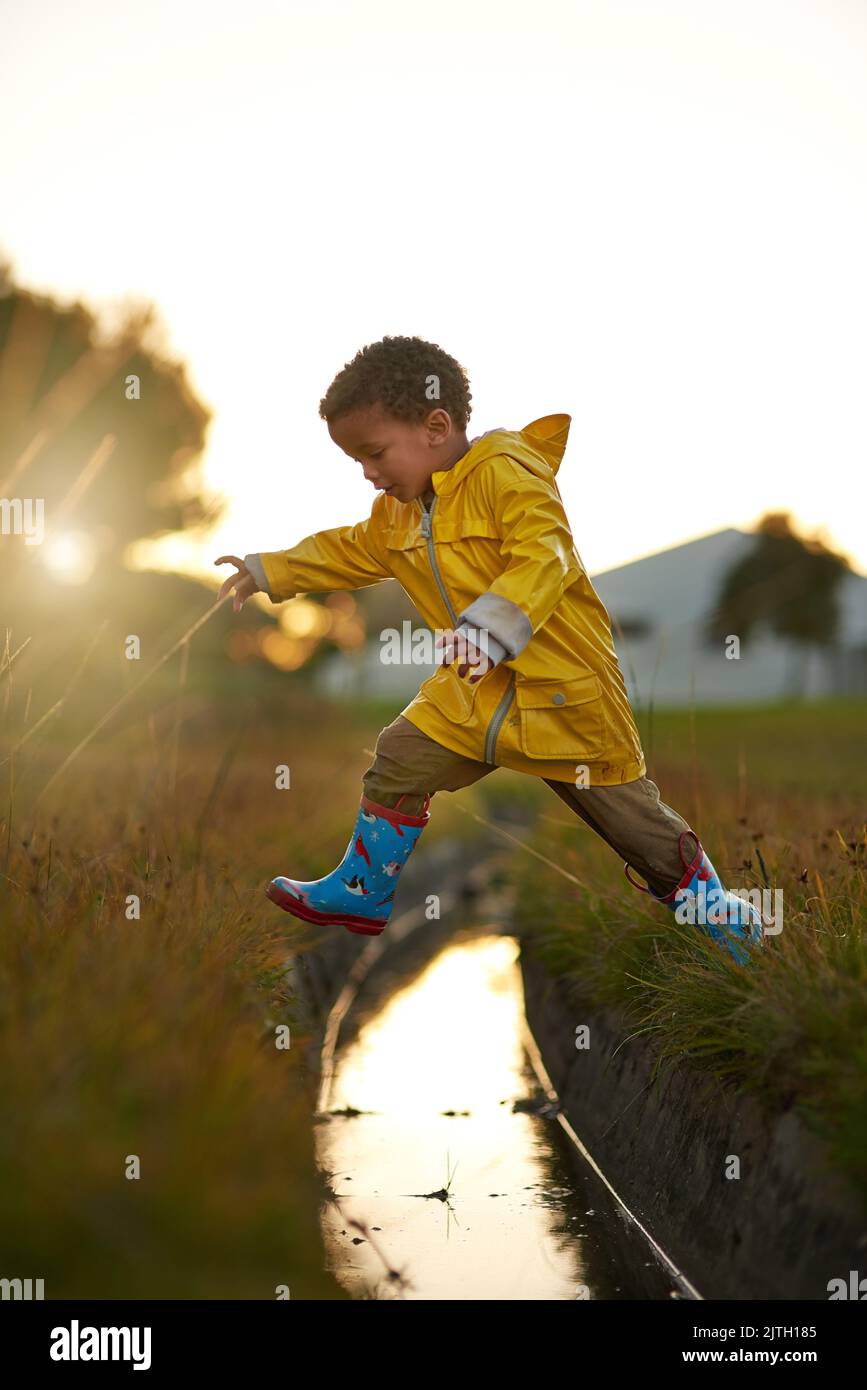 Un saut géant pour le boykind. Un petit garçon sautant sur l'eau en jouant à l'extérieur. Banque D'Images