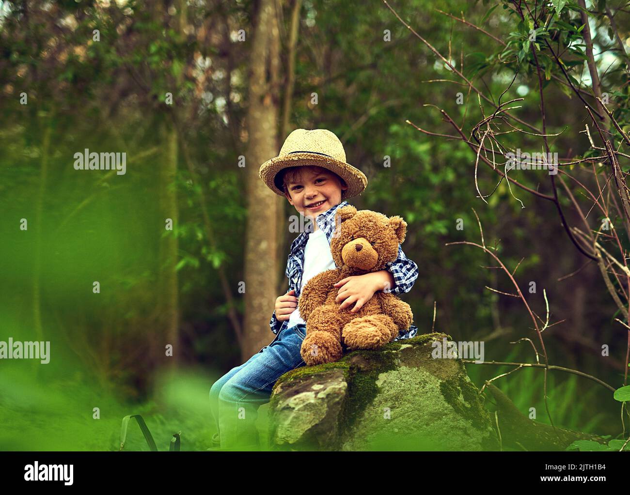 Teddy est très heureux quand on était à l'extérieur. Un petit garçon assis dans la forêt avec son ours en peluche. Banque D'Images