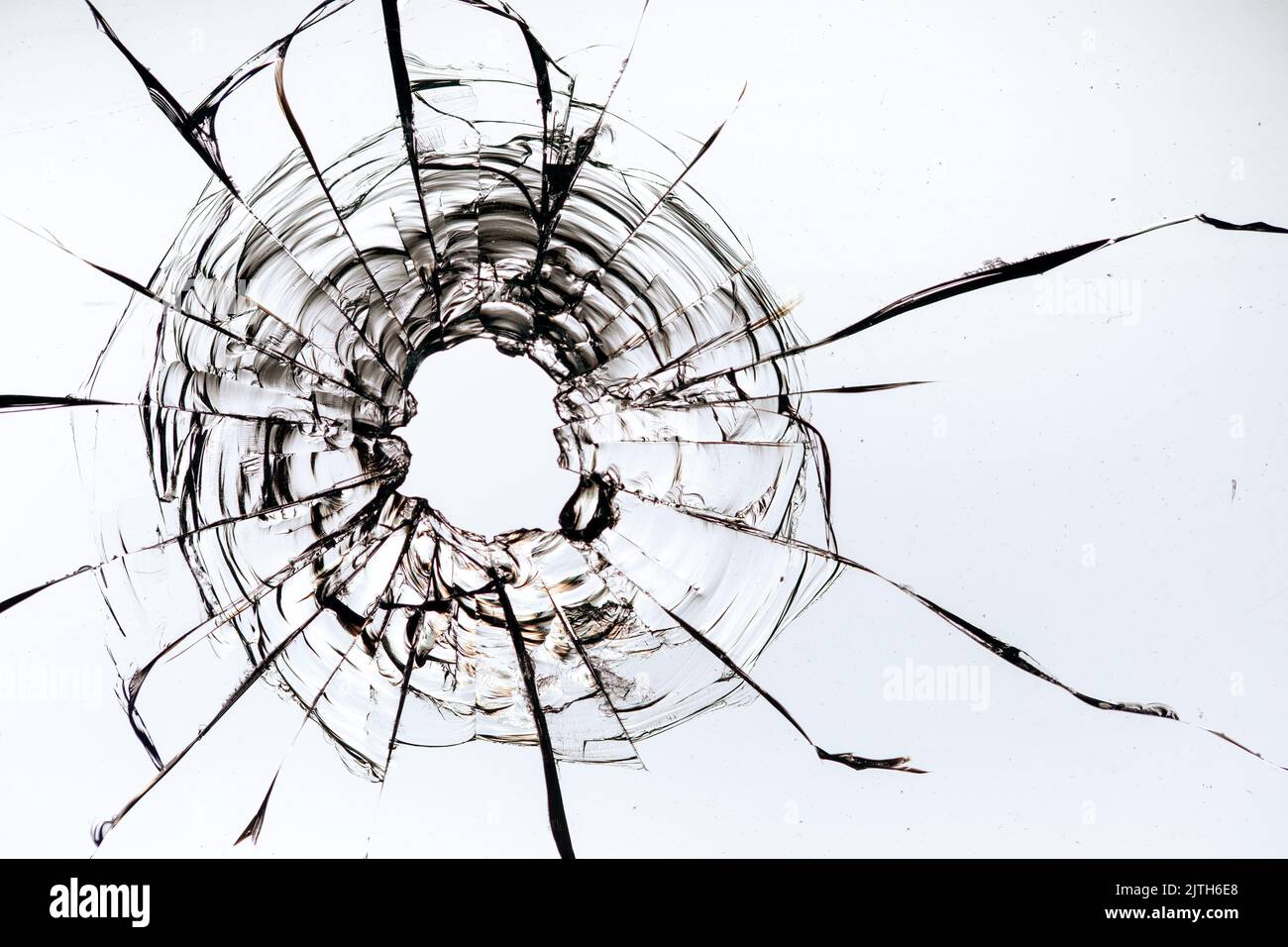 fissures dans le verre, un trou de balles dans le verre sur un fond blanc. Texture de verre de fenêtre. Banque D'Images