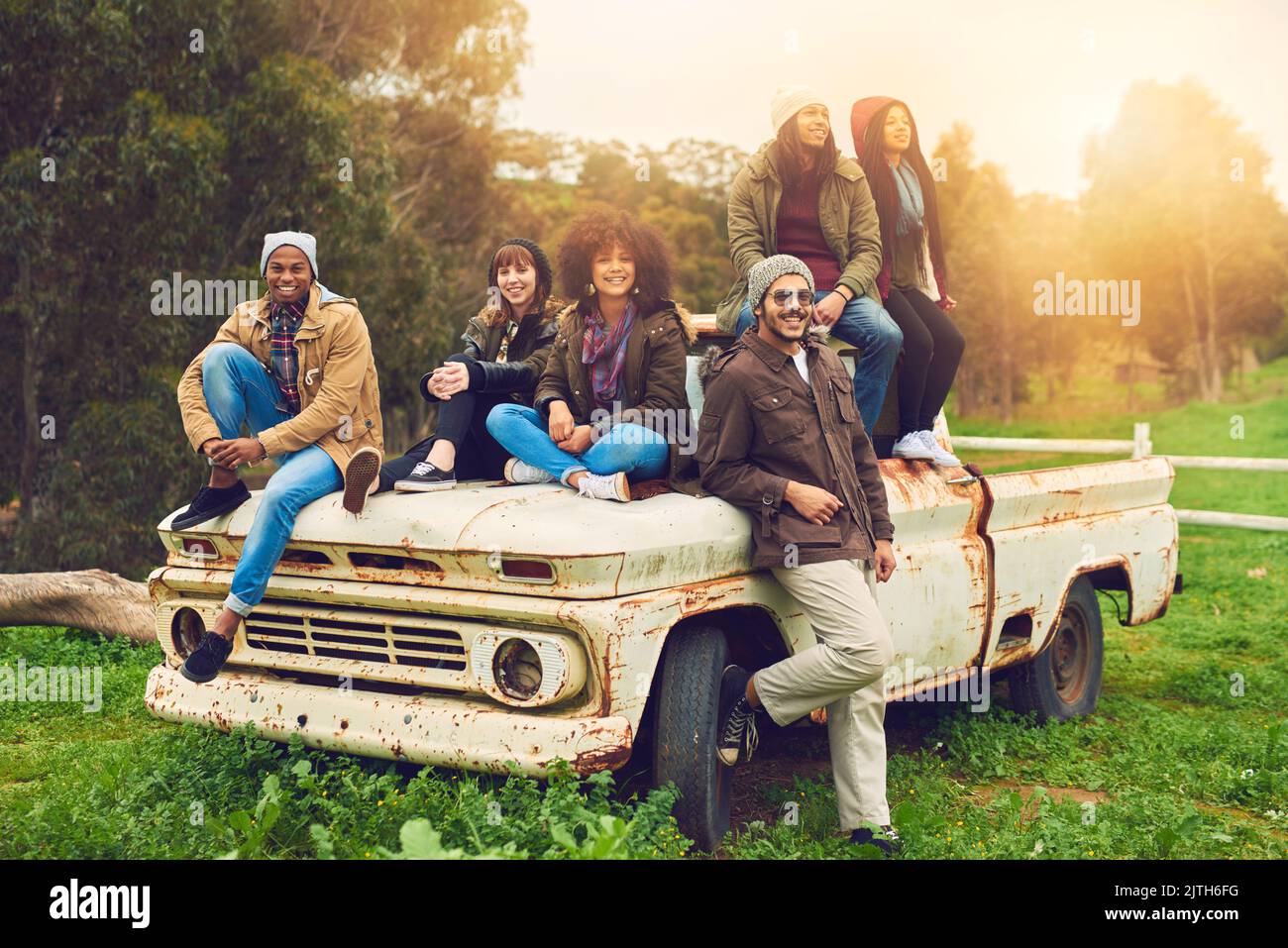 Temps froid, coeurs chauds. Portrait d'un groupe d'amis posé autour d'un vieux camion dans un champ. Banque D'Images