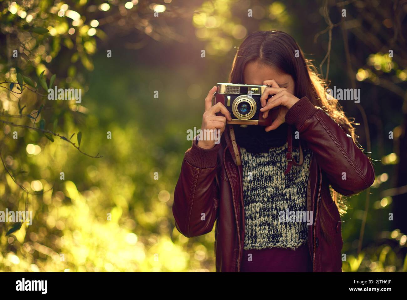 Le monde à travers un objectif est tout à fait étonnant. Une jeune fille qui prend des photos avec un appareil photo d'époque en plein air. Banque D'Images