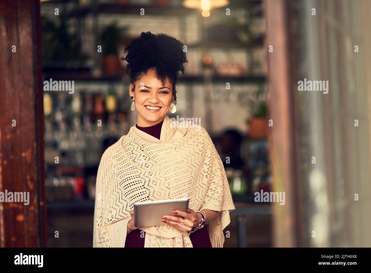 J'adore pouvoir accéder instantanément en ligne où que je me trouve. Portrait d'une jeune femme attrayante utilisant une tablette numérique dans un café. Banque D'Images
