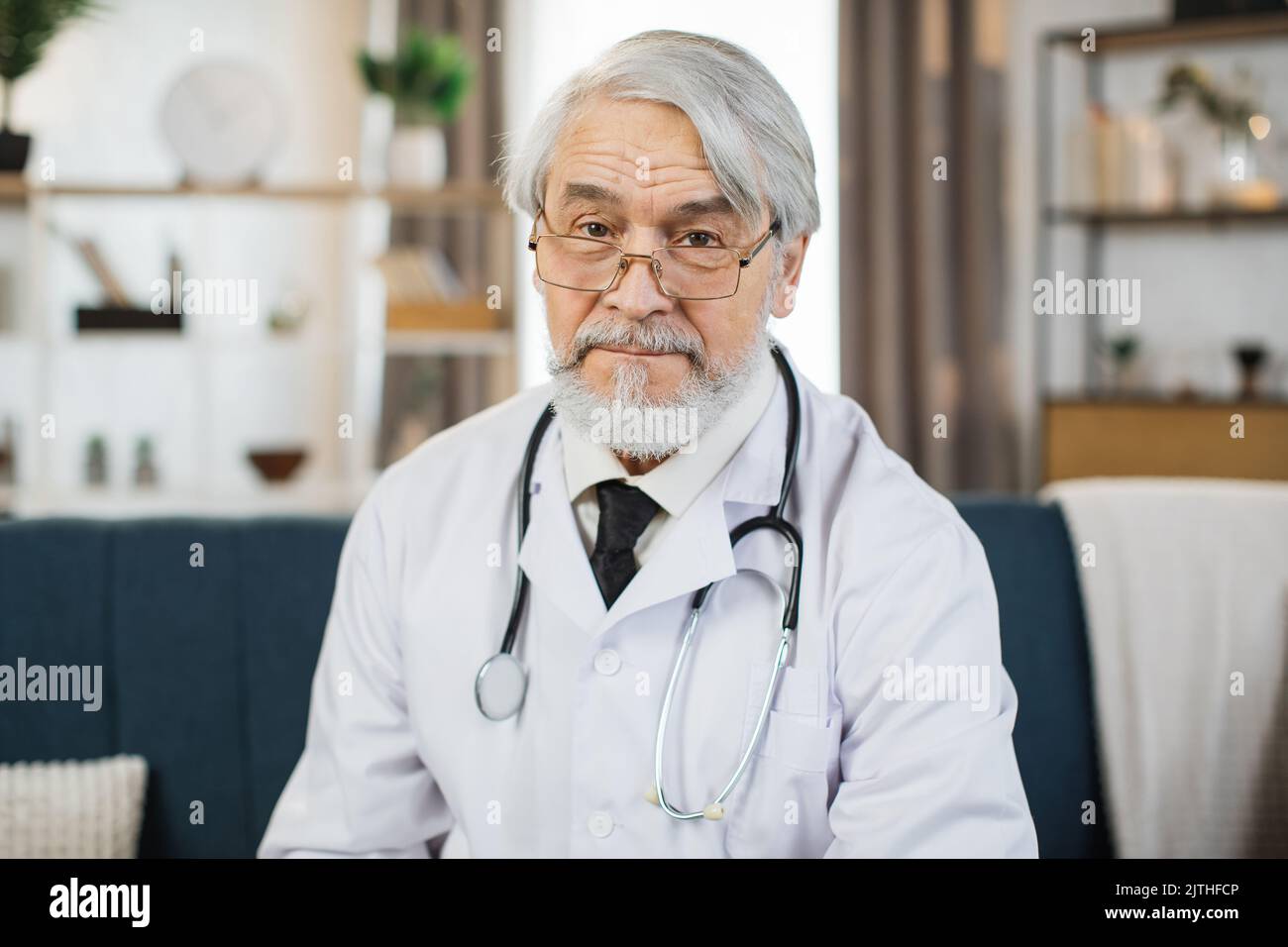 Un médecin de laboratoire assidu et des lunettes regardant la caméra pendant qu'il est assis au bureau de l'hôpital. Portrait d'un travailleur médical qualifié. Banque D'Images