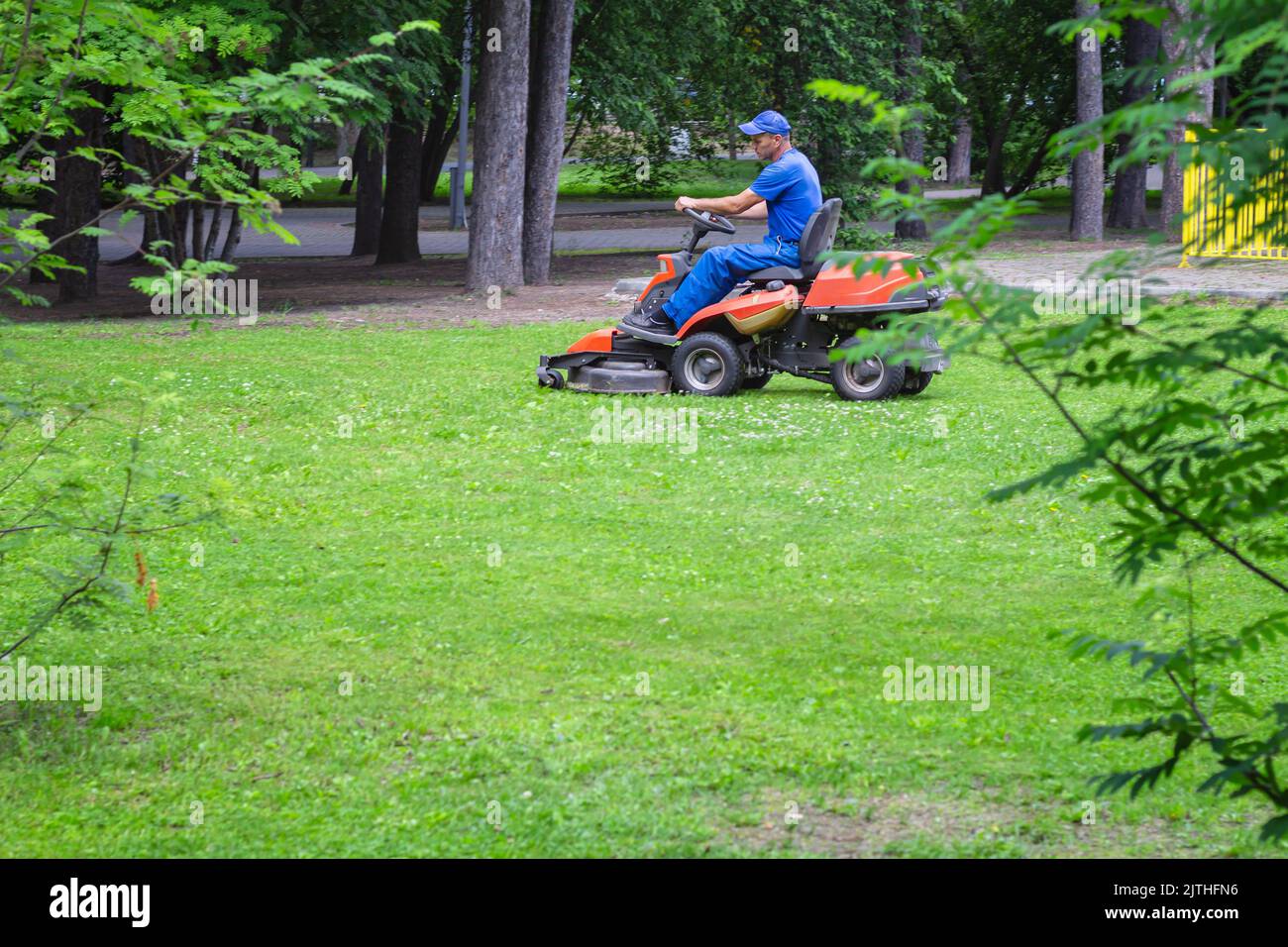 tondeuse à essence. Conduite d'une tondeuse à essence en plein air dans un parc. Utilisation de la technologie dans l'entretien des sols horticoles. Vue latérale du conducteur Banque D'Images