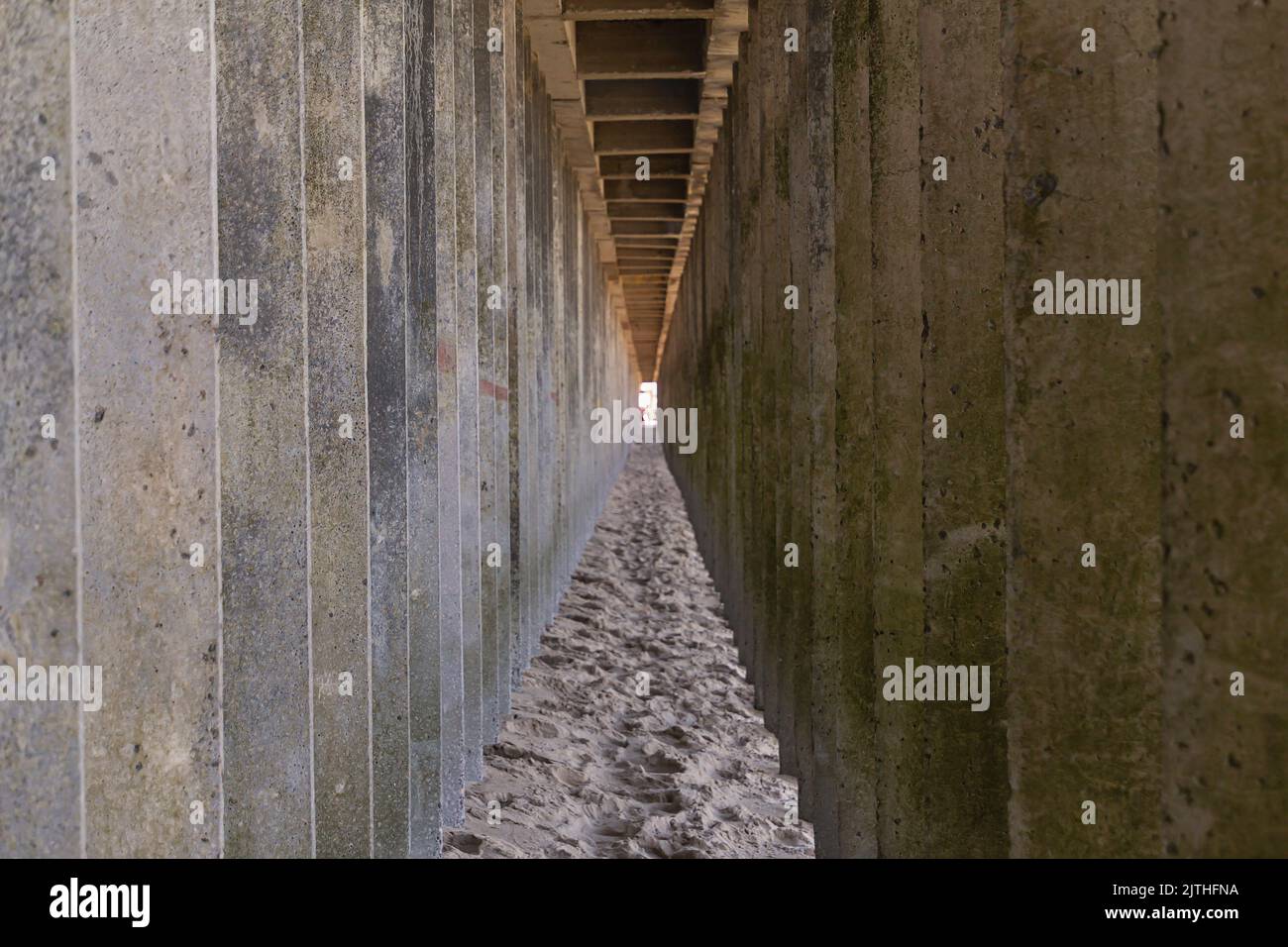 Arrière-plan géométrique abstrait, perspective horizontale de tir, pieux de béton sous la jetée, galerie de pieux de béton dirigé vers le milieu de la balle vers la lumière Banque D'Images