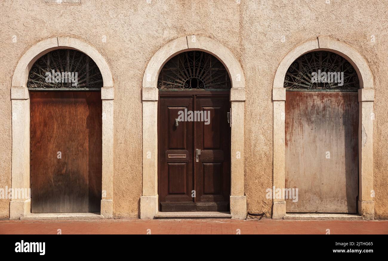 Mur en pierre avec trois portes voûtées. Porte en bois d'époque, vue avant Banque D'Images