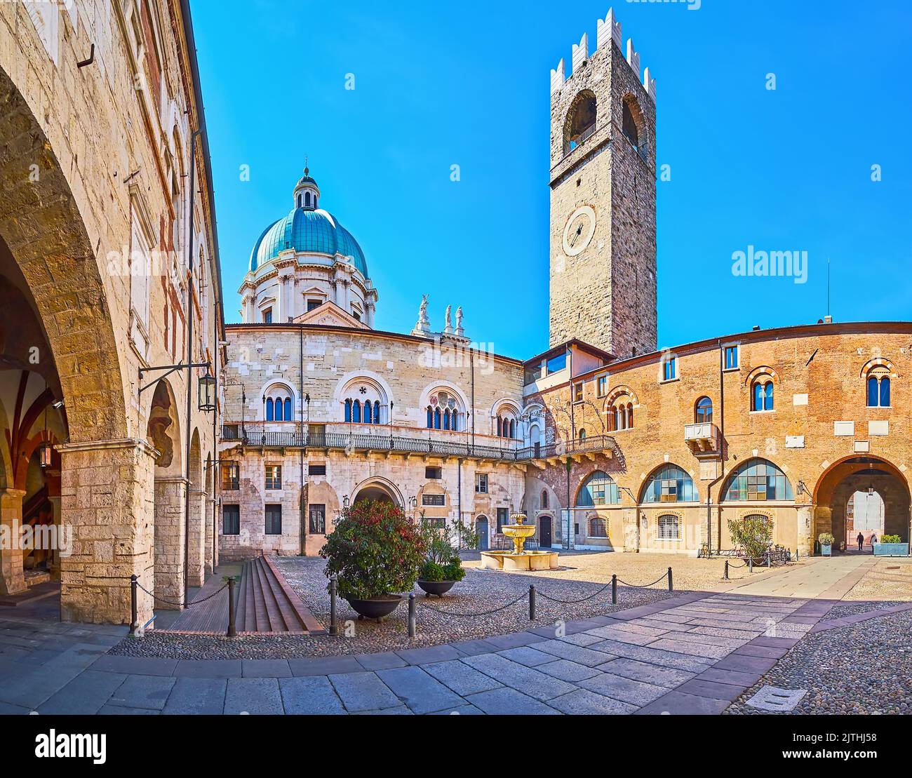 Panorama de la cour du Palazzo Broletto avec fontaine en pierre sculptée, tour Torre del pegol et arcade avec fresques, Brescia, Lombardie, Italie Banque D'Images