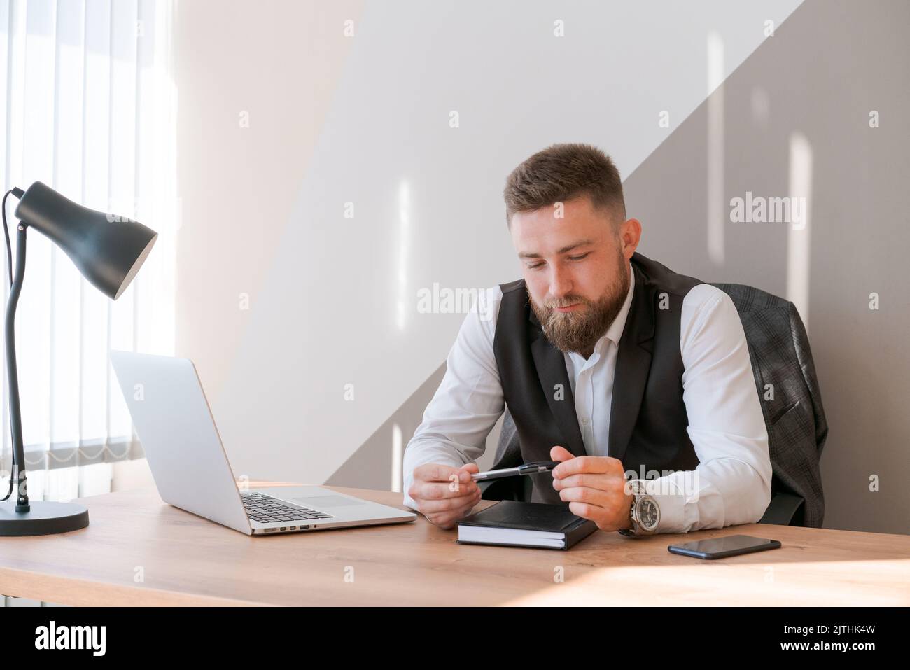 Beau homme d'affaires travaille avec un ordinateur portable au bureau ...