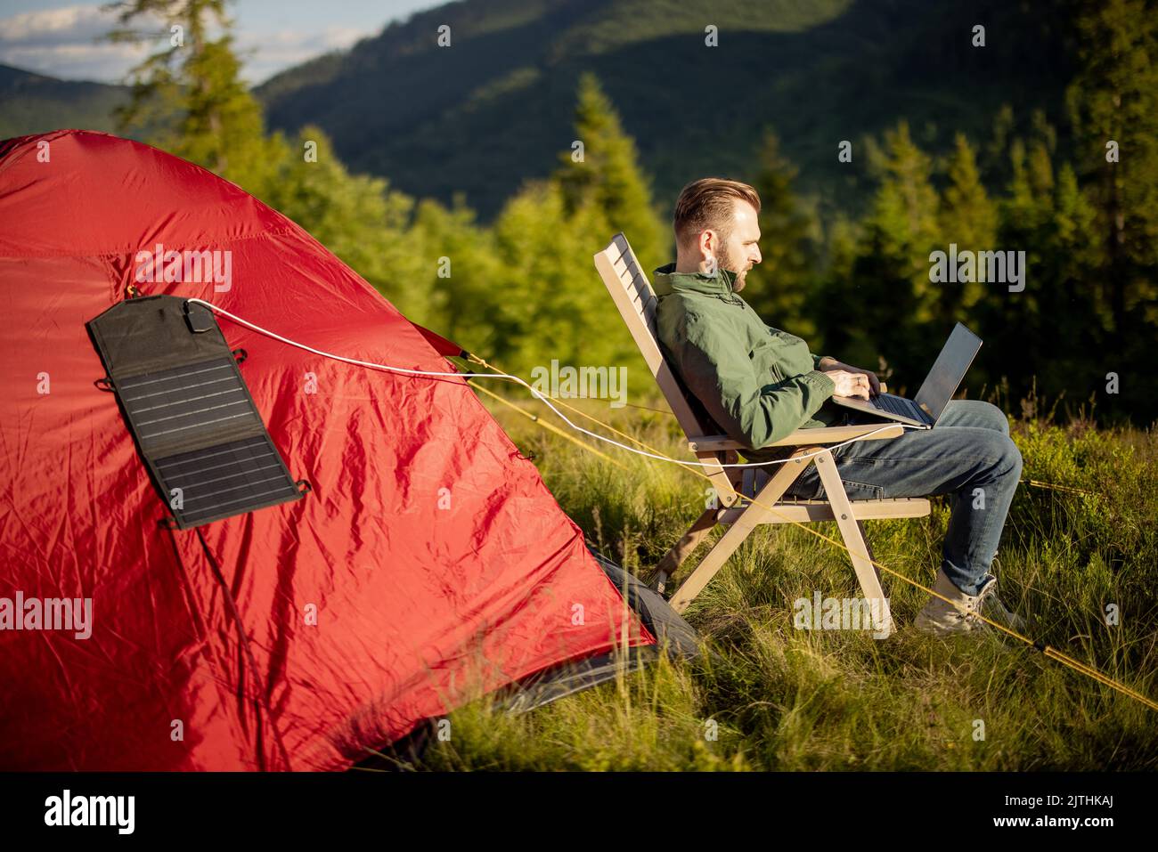 L'homme travaille sur ordinateur portable au camping dans les montagnes Banque D'Images
