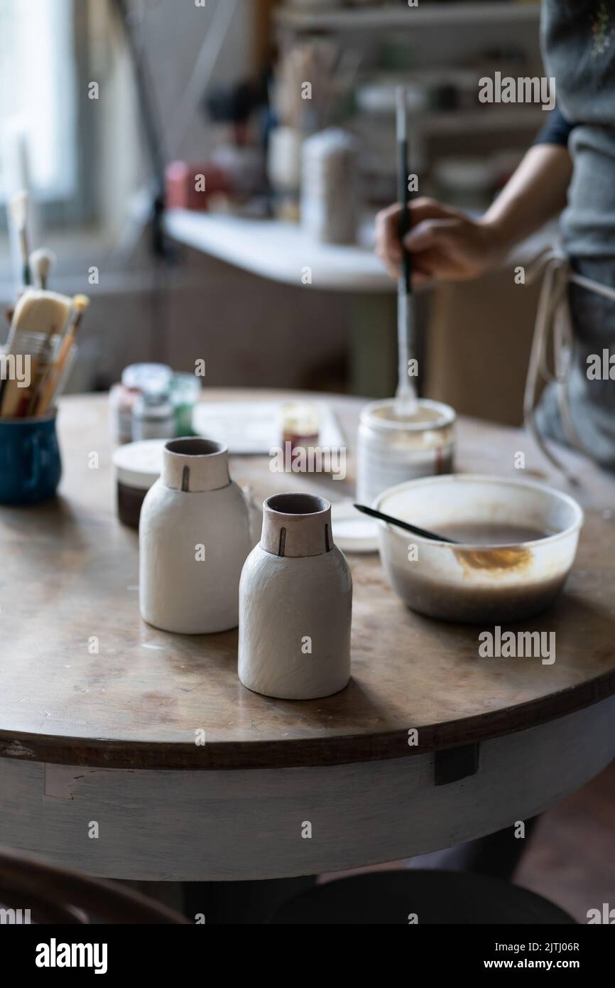 Photo de récolte de maître laissant des vases en argile à sécher sur table ronde dans le magasin de gros plan Banque D'Images