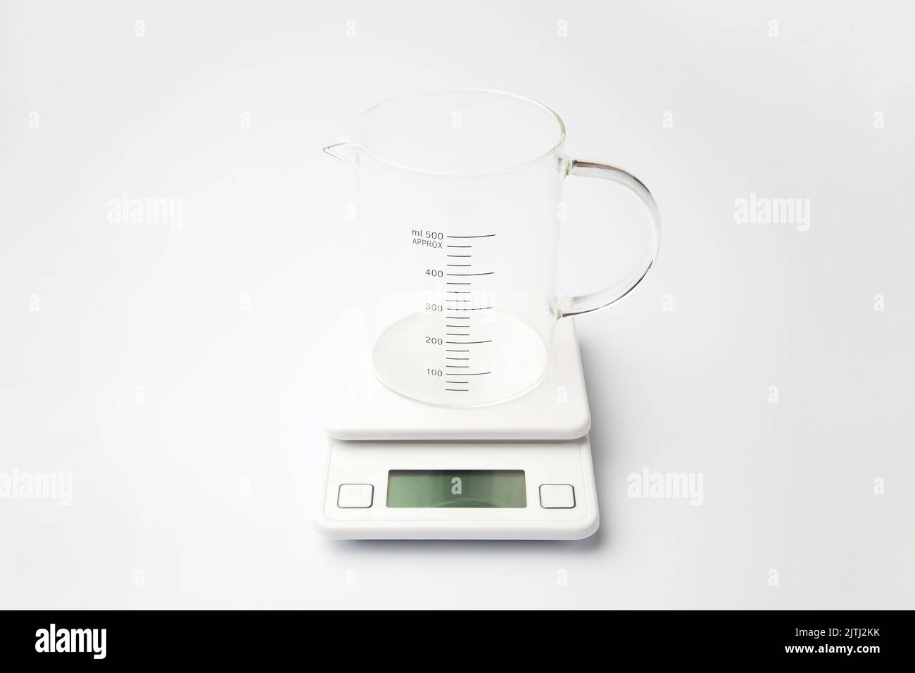 verre mesureur sur instrument de pesage électronique isolé sur fond blanc Banque D'Images