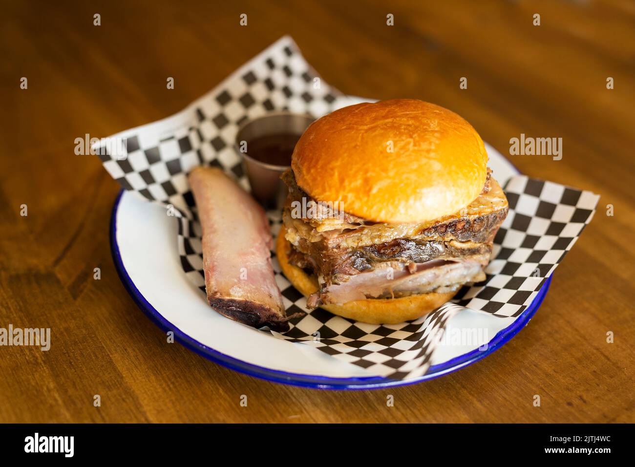 Hamburger avec côtes de bœuf et son os sur une assiette blanche sur une table en bois Banque D'Images