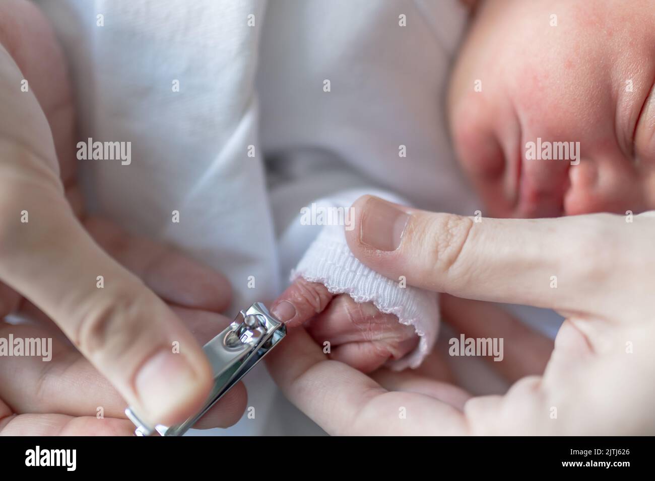 les mains d'une maman se coupant soigneusement les ongles de son nouveau-né pendant qu'il dort à l'hôpital de maternité. soins et attention à la santé et au corps o Banque D'Images