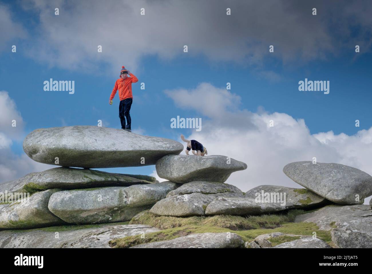 Un marcheur portant une veste rouge vif debout sur une immense pile de pierres de granit au sommet de la colline de Stowes sur le robuste Bodmin Moor dans Cornwall, aux États-Unis Banque D'Images