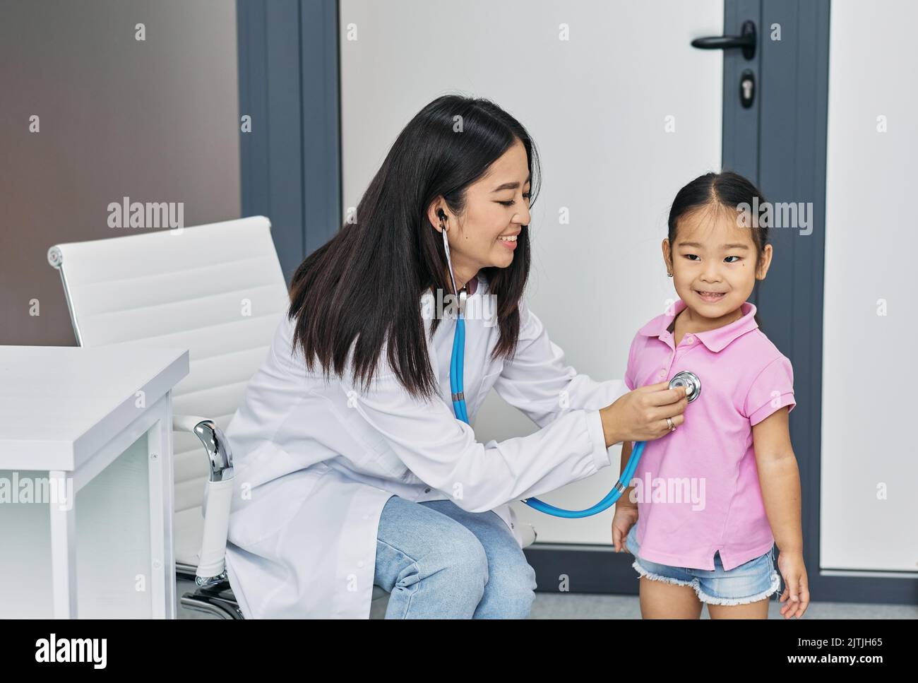 Pédiatre ausculting poumons de petite fille asiatique en utilisant stéthoscope pendant la consultation du médecin en clinique médicale Banque D'Images