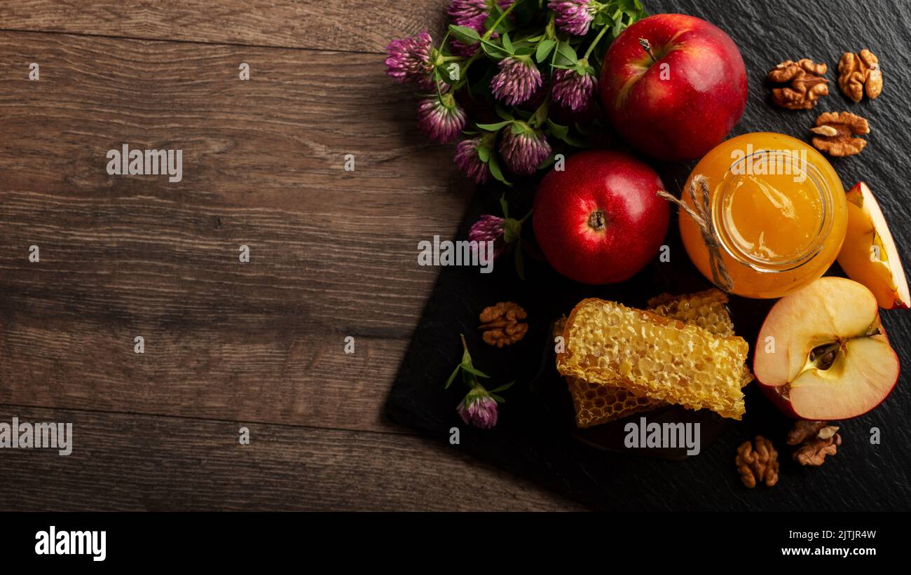 Pot Mason avec miel, nid d'abeille, pommes rouges et noix sur la table de cuisine Banque D'Images