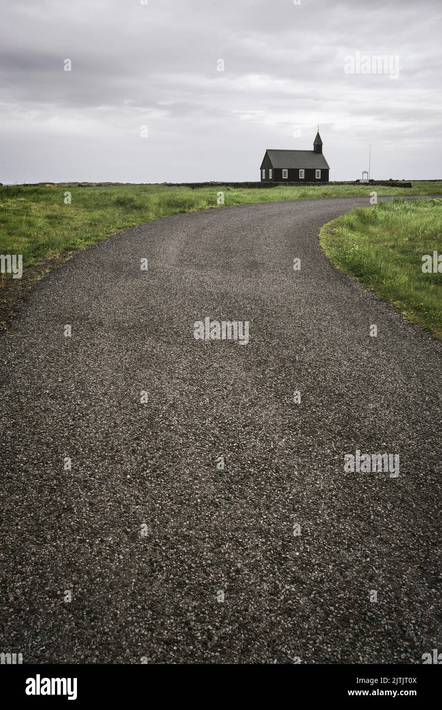 Route menant à l'église en bois noir Budakirkja dans le village de Budhir, Islande Banque D'Images