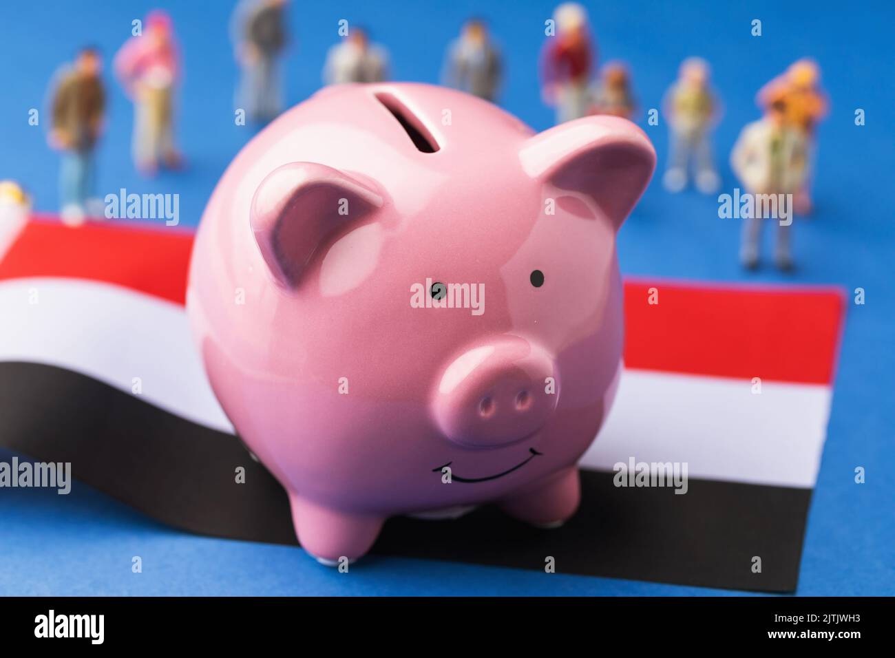 La banque de porc, le drapeau et les jouets en plastique sur un fond coloré, le concept du revenu de la population égyptienne Banque D'Images