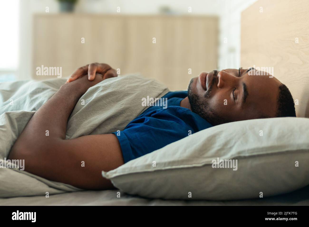 Homme afro-américain appréciant un sommeil sain se reposant dans la chambre Banque D'Images