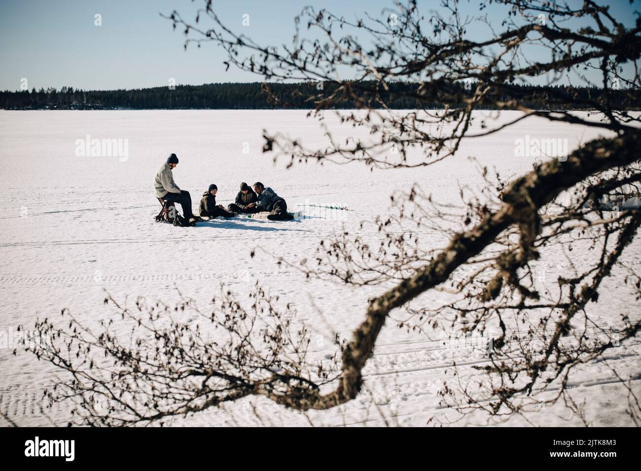 Les pères avec des fils pêchent sur la glace le jour ensoleillé en hiver Banque D'Images
