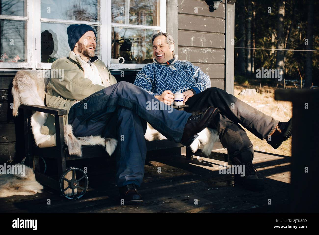 Joyeux hommes mûrs parlant tout en ayant le café ensemble au porche pendant l'hiver Banque D'Images