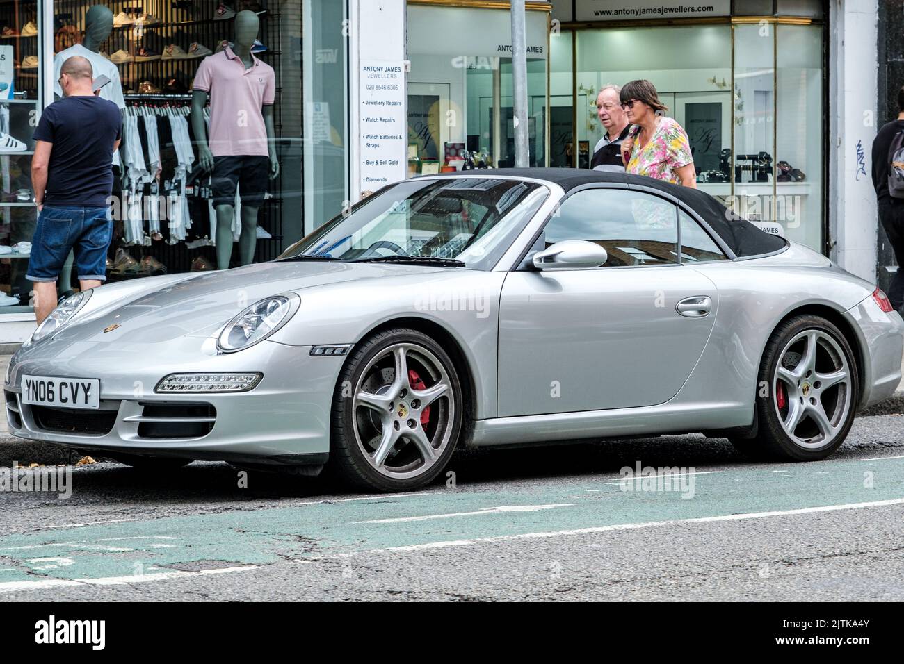 Kingston-upon-Thames, Londres, Royaume-Uni, 29 août 2022, Porsche 911 argent convertable garée sur Une rue principale avec des acheteurs naviguant dans les fenêtres de magasin Banque D'Images