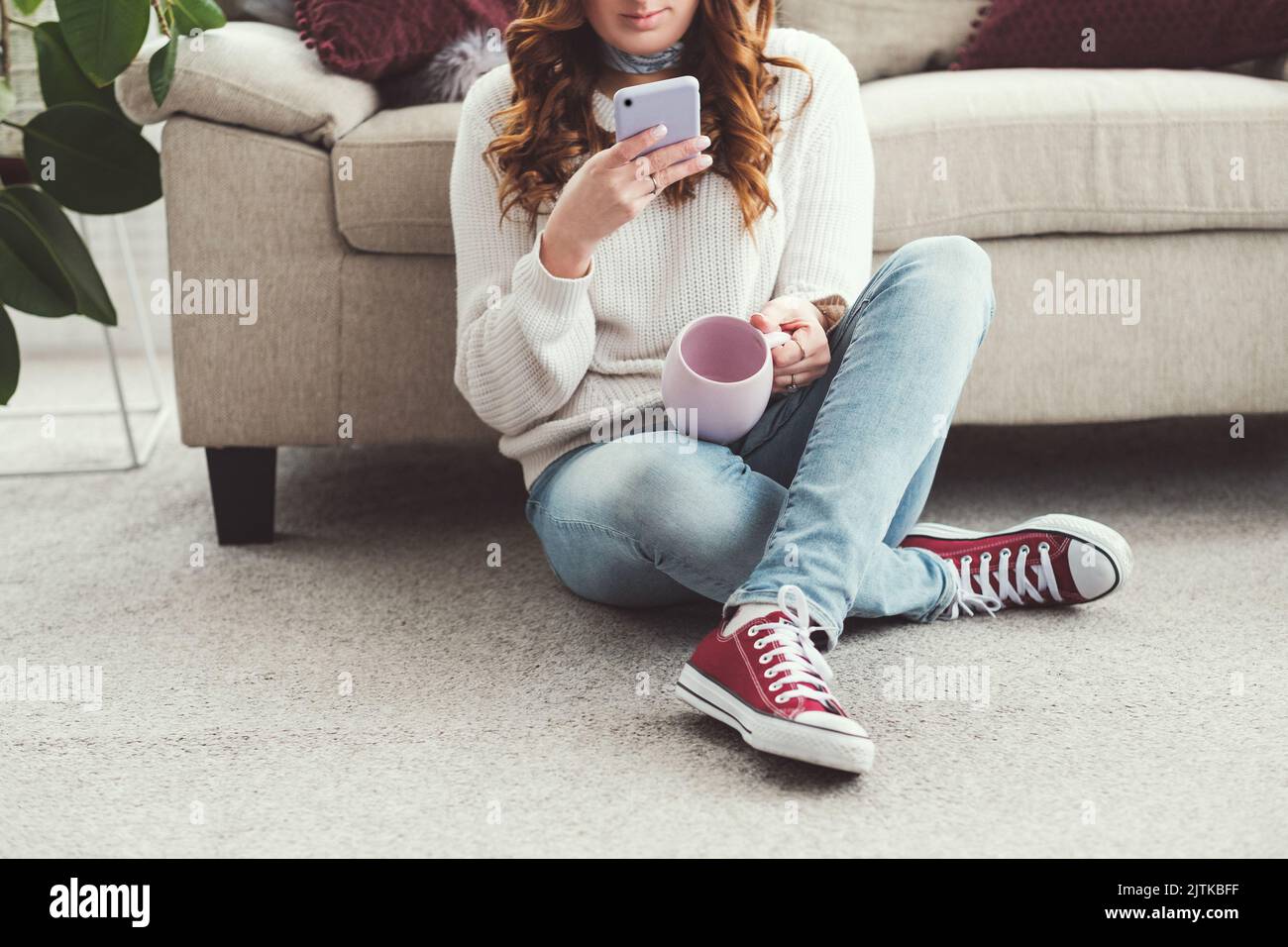 femme loisirs confortable maison tasse de navigation smartphone Banque D'Images