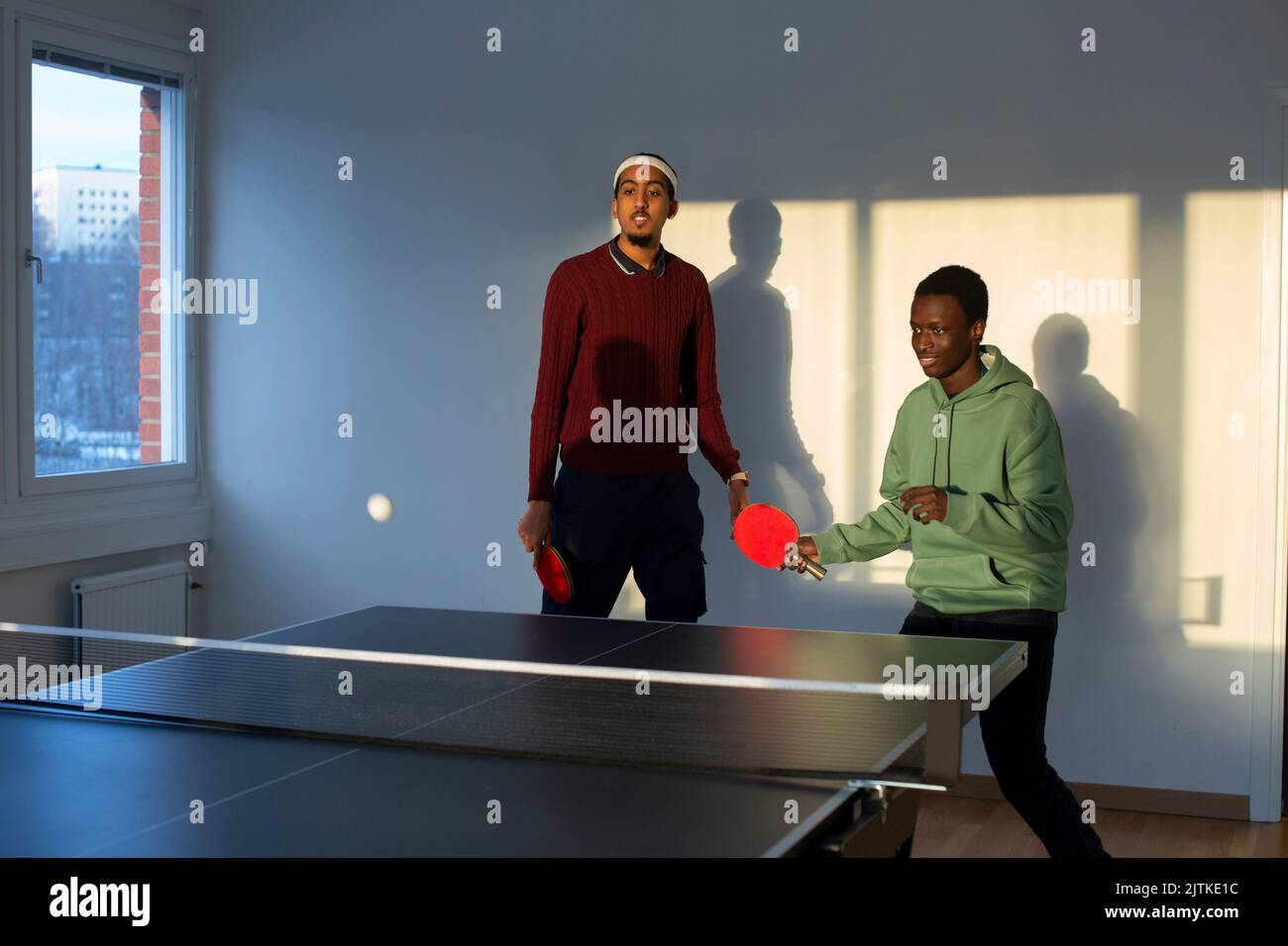Amis jouant au tennis de table dans la salle de jeux Banque D'Images