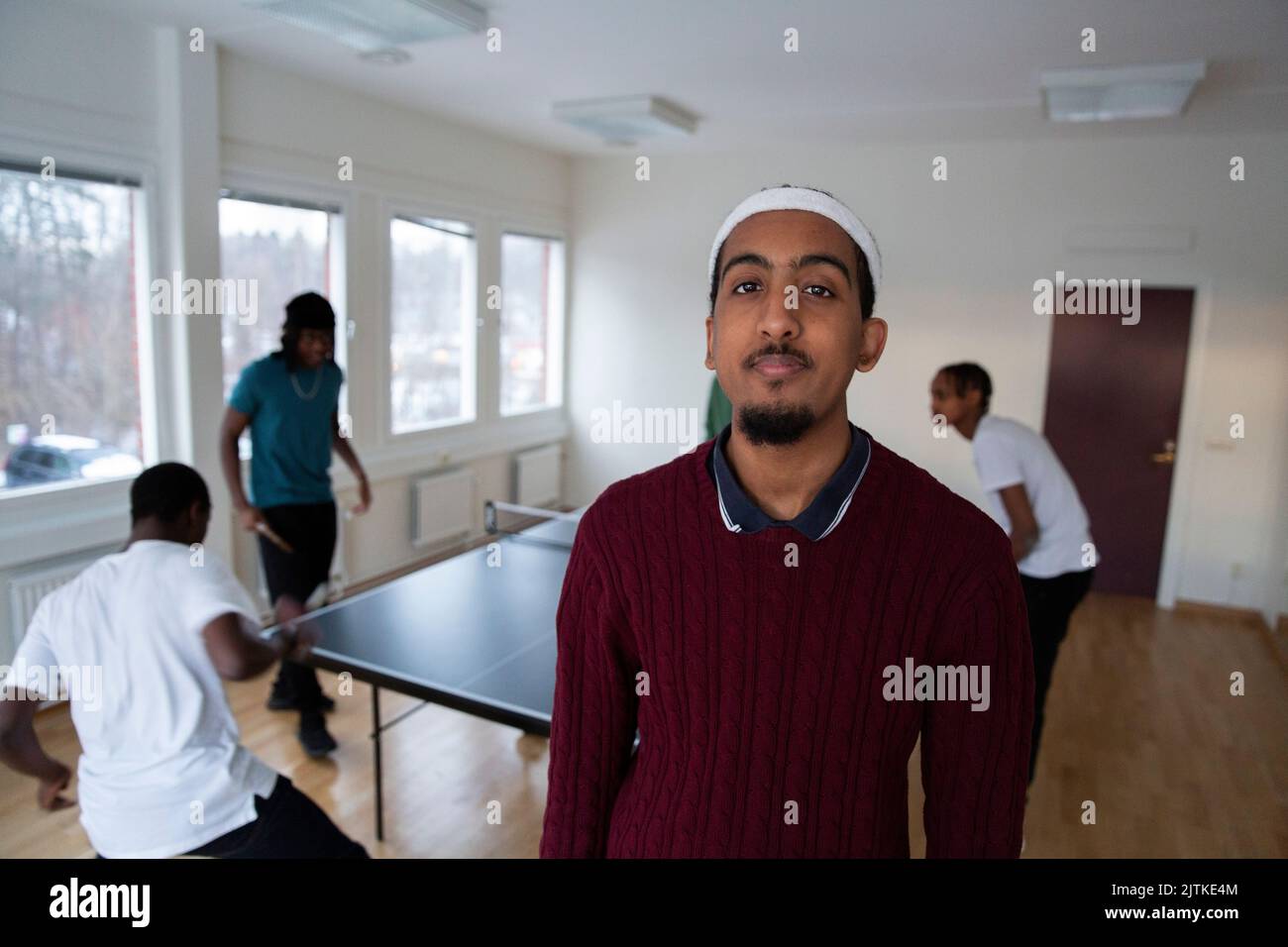 Portrait d'un homme debout pendant que des amis jouent au tennis de table en arrière-plan dans la salle de jeux Banque D'Images