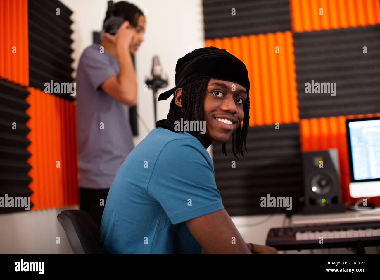 Compositeur de musique souriant assis dans un studio d'enregistrement Banque D'Images
