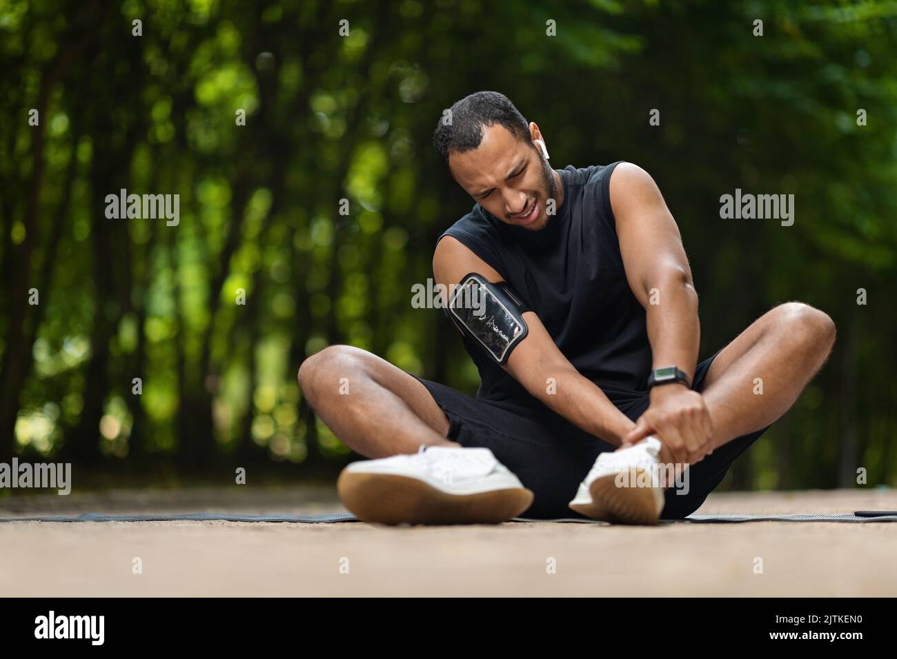 Sportif afro-américain dans la douleur touchant sa cheville, copier l'espace Banque D'Images