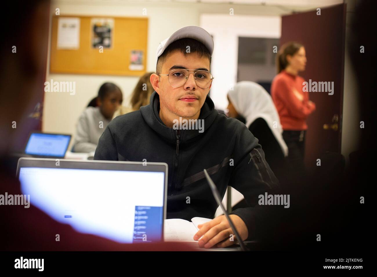 Élève avec chapeau et lunettes assis en classe Banque D'Images