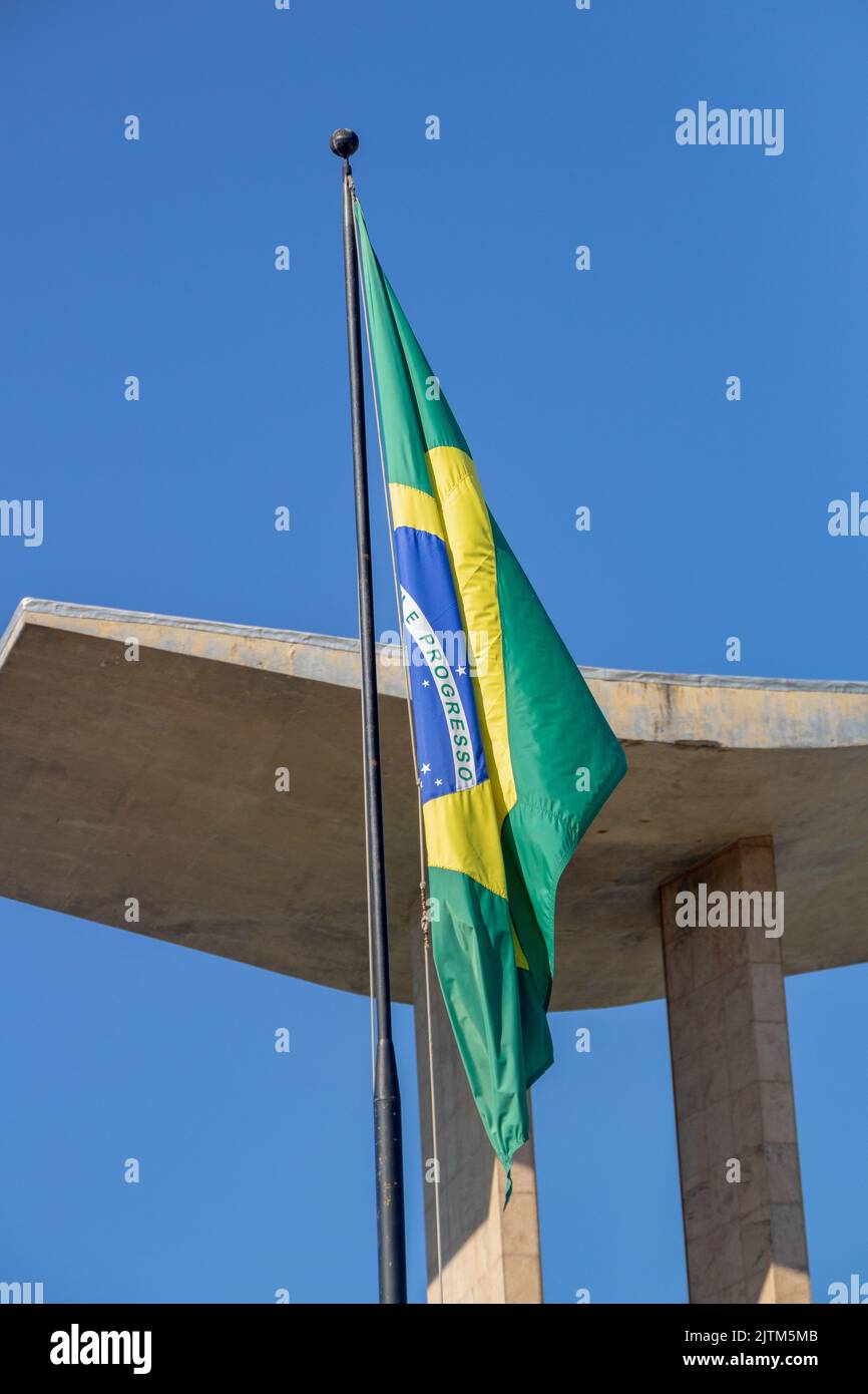 Drapeau brésilien avec ciel bleu en arrière-plan et monument à Rio de Janeiro, Brésil. Banque D'Images