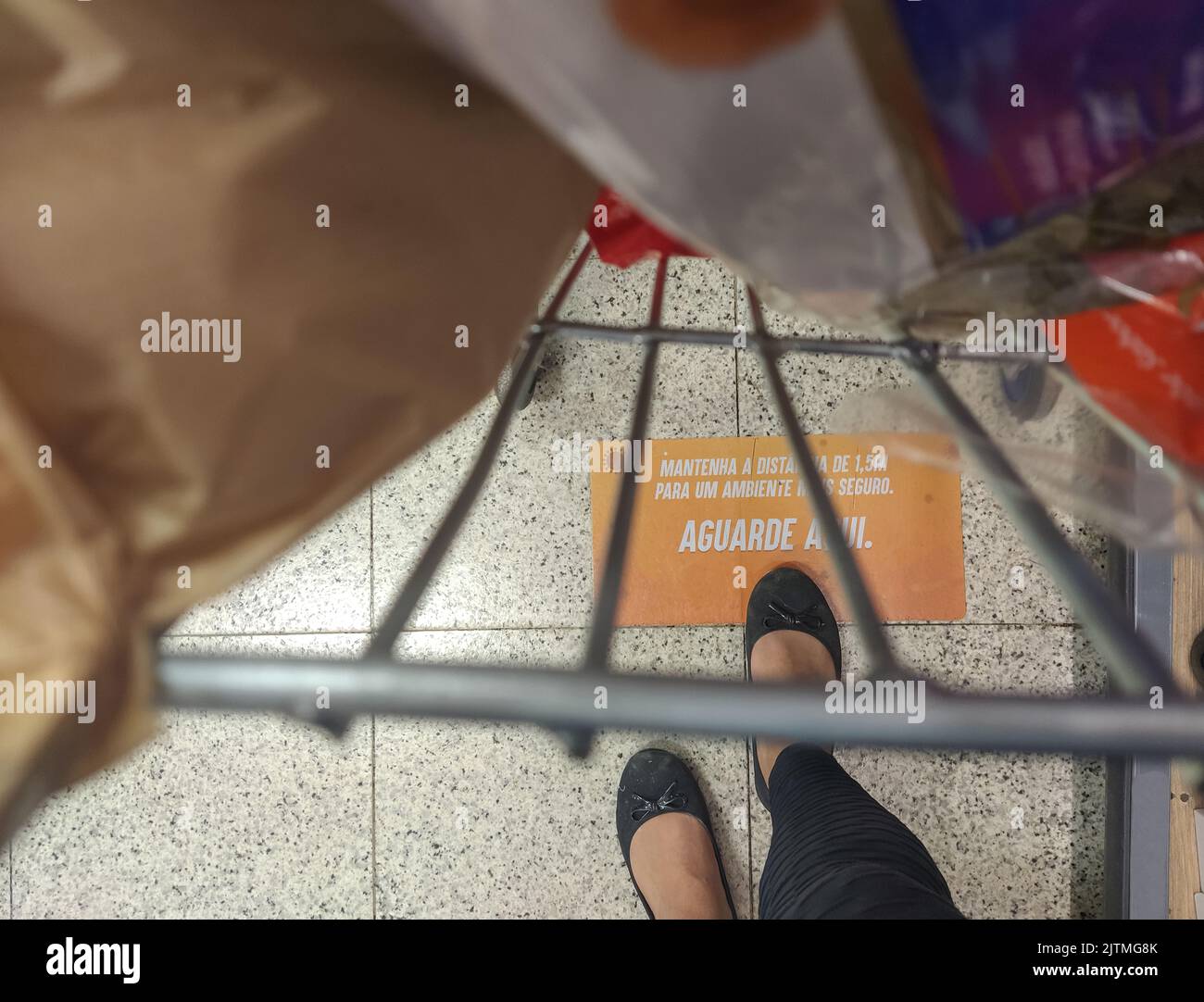 pieds féminins à côté d'un panier avec un panneau sur l'étage écrit en portugais (garder la distance 1,5 mètres pour un environnement sûr) règles pendant Banque D'Images