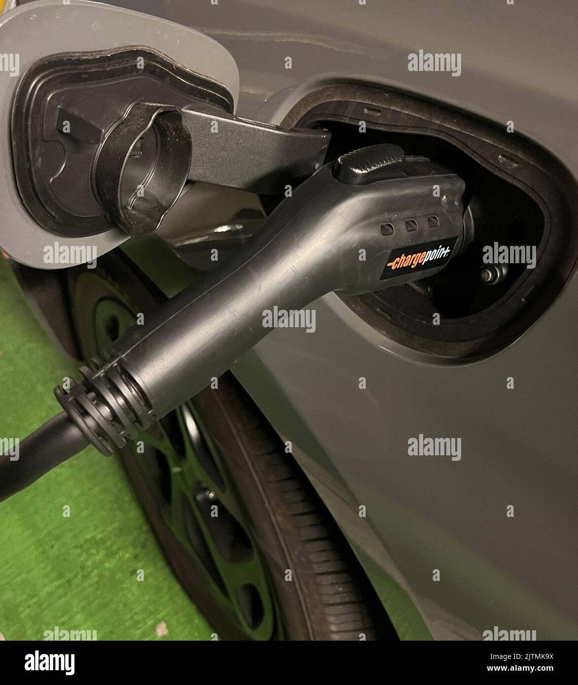 Mini-fourgonnette hybride branchée à une station de charge ChargePoint. Banque D'Images
