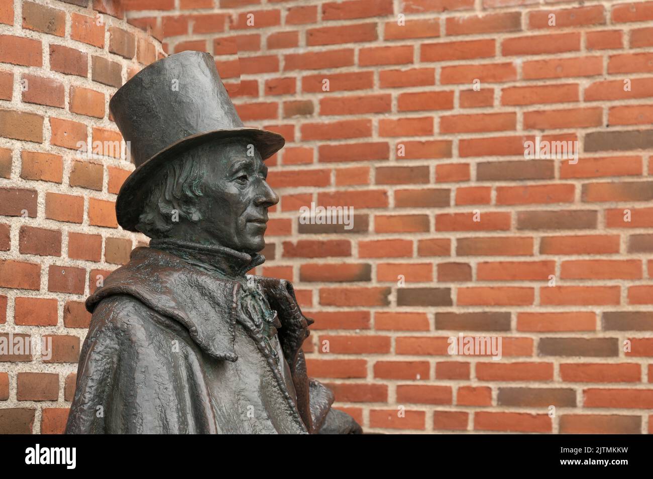 Statue en bronze de l'auteur danois H C Andersen assis en profil contre un mur de briques rouges, Odense, Danemark, 28 août 2022 Banque D'Images