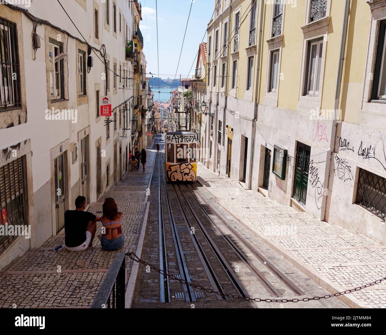 Couple assis et en admirant la scène comme un tramway approche dans le quartier de Baixa-Chiado de Lisbonne surplombant le Tage. Portugal. Banque D'Images