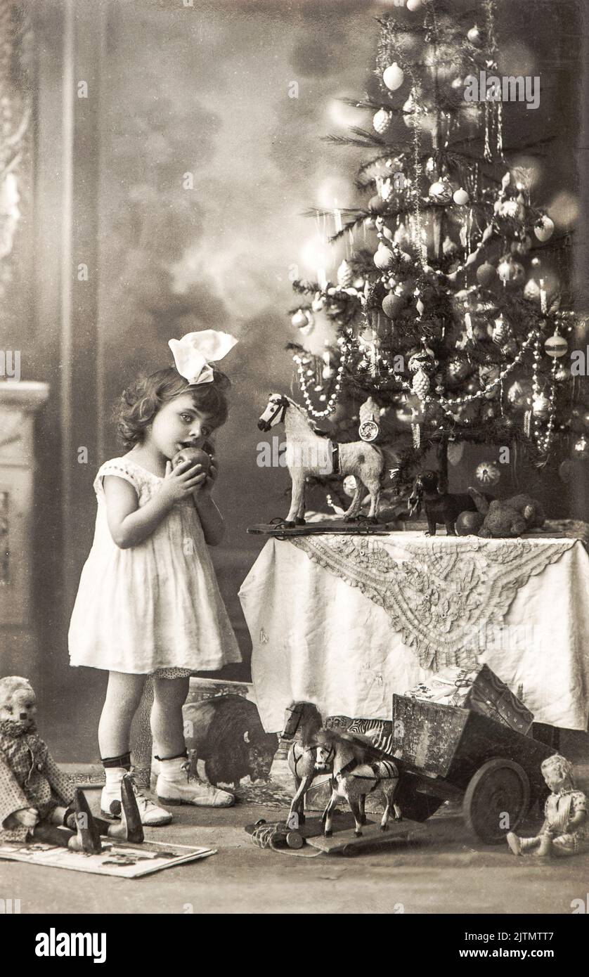 Petite fille avec arbre de Noël et jouets vintage, vers 1900 Allemagne. Ancienne carte postale photo Banque D'Images