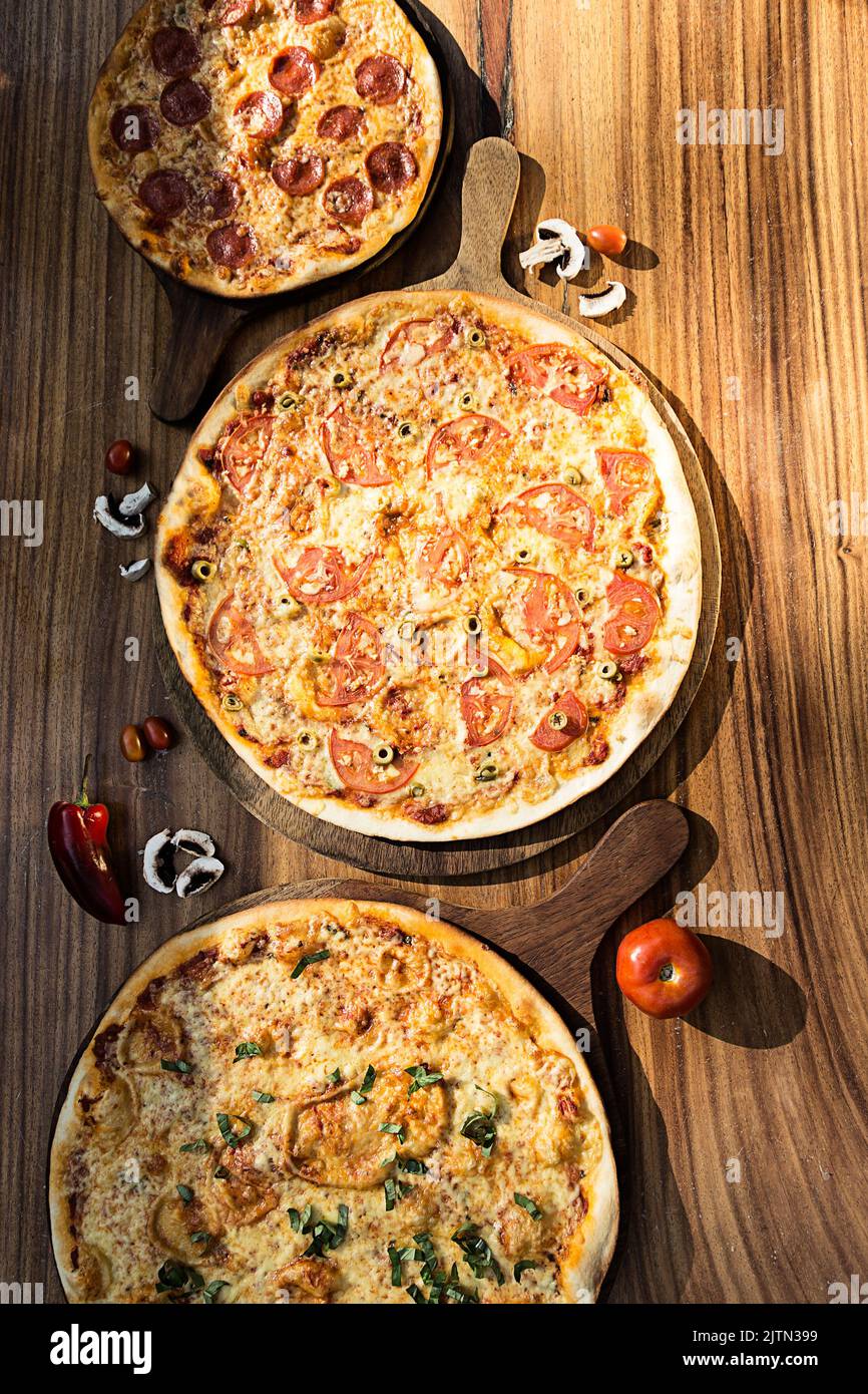 Trois pizzas aux saveurs différentes. Pepperoni, fromage, pomme de terre, oignon, tomate. Pizza italienne de qualité. Banque D'Images