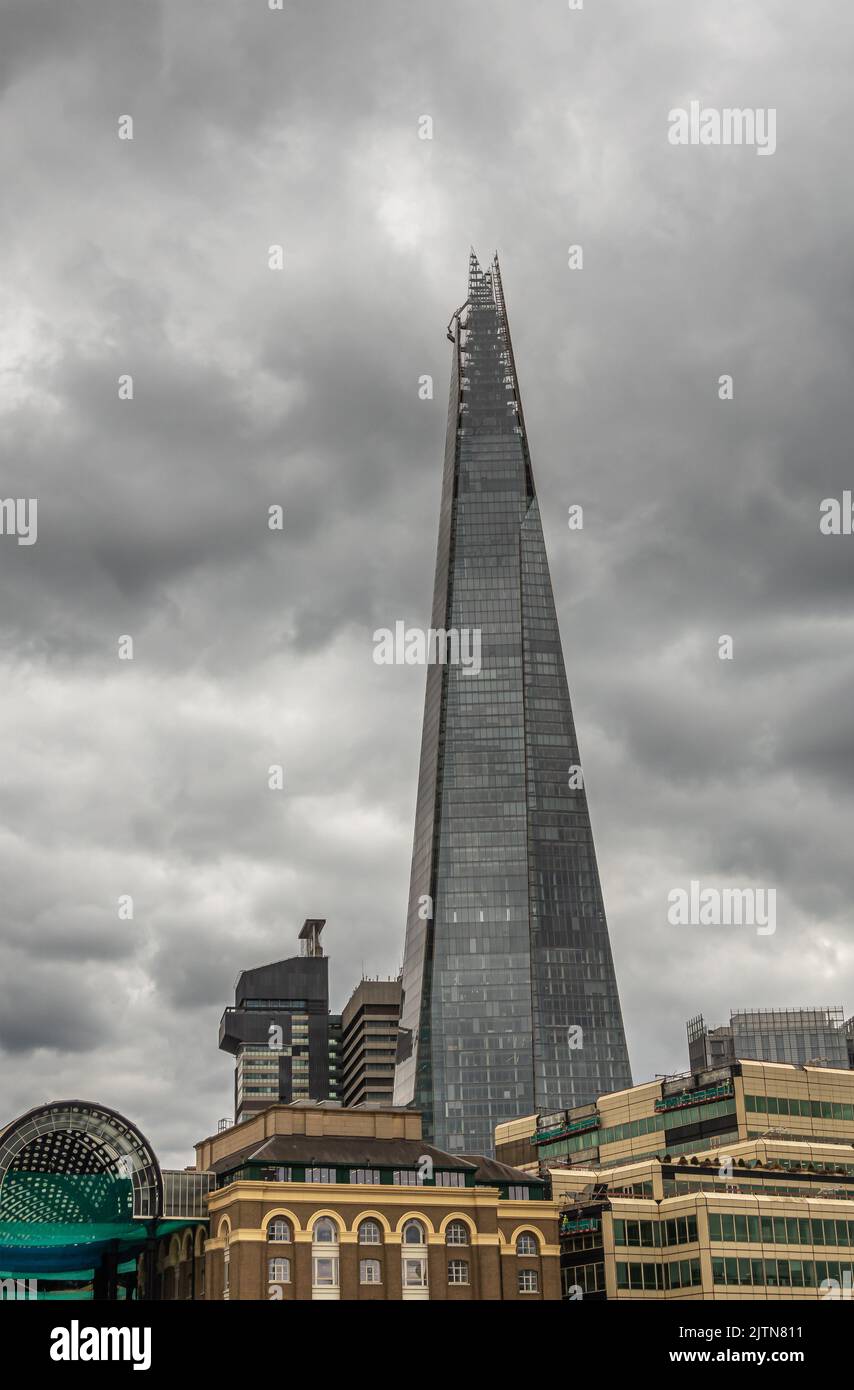 Londres, Angleterre, Royaume-Uni - 6 juillet 2022 : depuis la Tamise. Le gratte-ciel de Chard sous un paysage de nuages gris derrière le quai de Queens Walk avec l'hôpital London Bridge. Banque D'Images