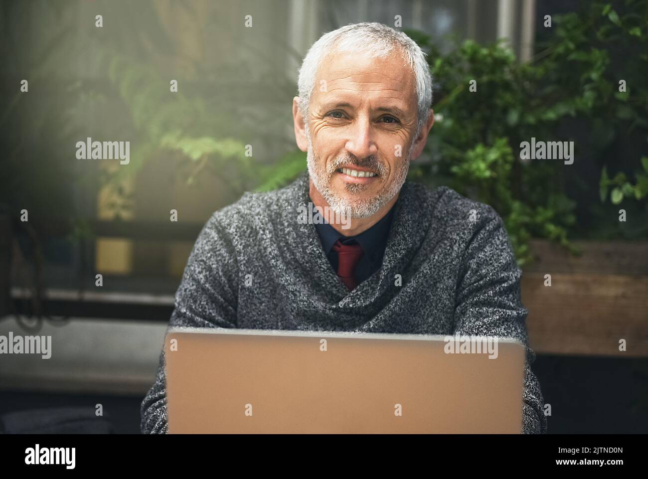 C'est mon endroit préféré pour faire un peu de travail. Portrait d'un homme d'affaires mature utilisant son ordinateur portable dans un café. Banque D'Images