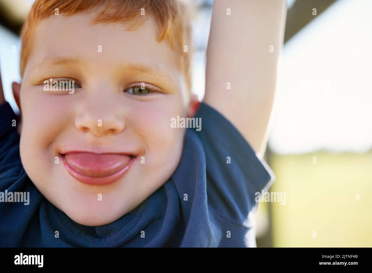 Neener Neener. Portrait d'un garçon qui colle de sa langue pendant qu'il est suspendu d'une salle de gym de la jungle. Banque D'Images