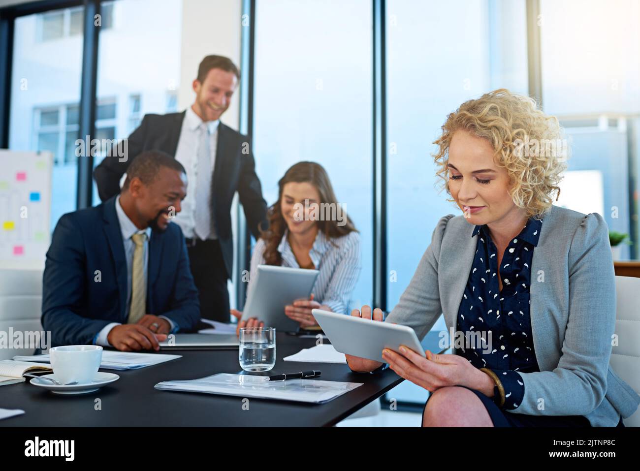 Beaucoup de mains font du travail léger. Une femme d'affaires travaillant dans la salle de réunion avec ses collègues en arrière-plan. Banque D'Images